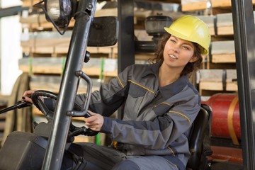 Young brunette female wearing in gray uniform and yellow helmet,  driving and making operating...