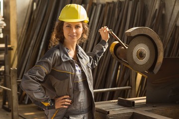 Smiling female brunette worker in warehouse working at machine tool for iron and metal and carving....