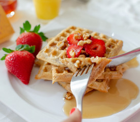 Desayuno saludable - waffles de harina del negrito, servidos con nueces, fresas, miel y jugo fresco