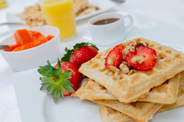 Desayuno saludable - waffles de harina del negrito, servidos con nueces, fresas, papaya, jugo fresco y café