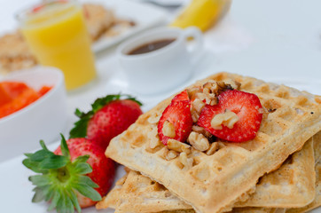 Desayuno saludable - waffles de harina del negrito, servidos con nueces, fresas, jugo fresco y café