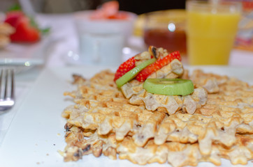 Desayuno saludable - waffles de harina del negrito, servidos con nueces, kiwi, fresas, miel, jugo fresco y café