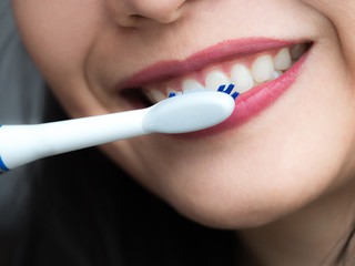 Fast moving electronic toothbrush and cleaning mouth, Smiling healthy pretty woman using a generic white electric toothbrush to brush her teeth in an oral hygiene, healthcare and dentistry concept.
