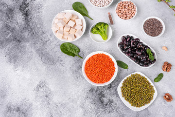 Superfoods on a gray background with copy space. Nuts, beans, greens and seeds. Healthy vegan food