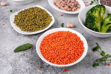 Superfoods on a gray background with copy space. Nuts, beans, greens and seeds. Healthy vegan food