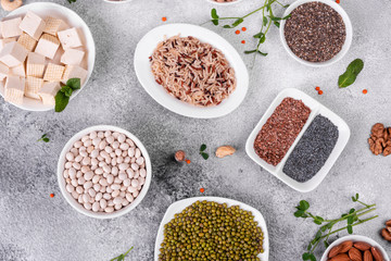 Superfoods on a gray background with copy space. Nuts, beans, greens and seeds. Healthy vegan food