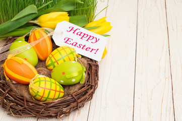 Easter decoration with eggs and tulips with the words happy easter on a wooden background.