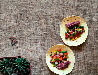 Traditional dish of Mexican cuisine. Corn tortilla tacos with vegetable filling on  burlap texture. 