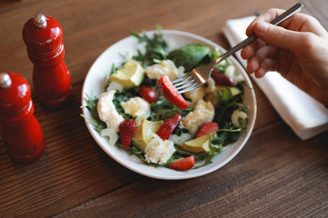 POV, male hand eating fresh salad, strawberry on a fork