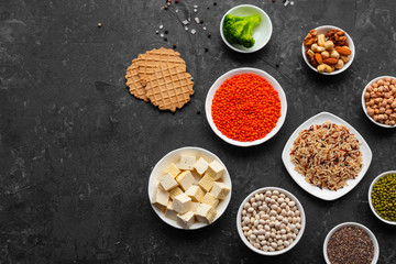 Superfoods on a gray background with copy space. Nuts, beans, greens and seeds. Healthy vegan food