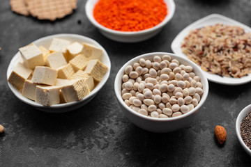 Superfoods on a gray background with copy space. Nuts, beans, greens and seeds. Healthy vegan food