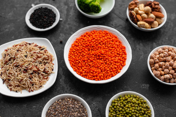 Superfoods on a gray background with copy space. Nuts, beans, greens and seeds. Healthy vegan food