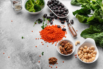 Superfoods on a gray background with copy space. Nuts, beans, greens and seeds. Healthy vegan food
