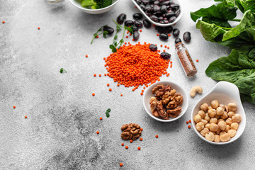 Superfoods on a gray background with copy space. Nuts, beans, greens and seeds. Healthy vegan food