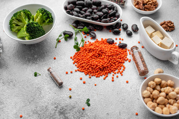 Superfoods on a gray background with copy space. Nuts, beans, greens and seeds. Healthy vegan food