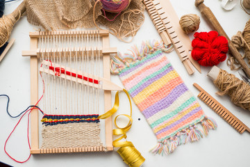 Tools for weaving and thread lie on a white table