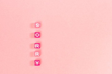 sorry  inscription made of colorful cube beads with letters. Festive pink background concept with...