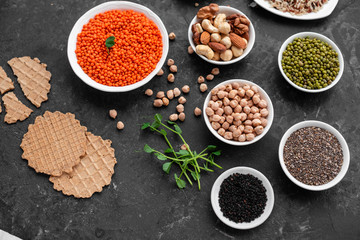 Superfoods on a gray background with copy space. Nuts, beans, greens and seeds. Healthy vegan food