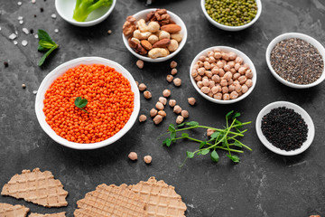 Superfoods on a gray background with copy space. Nuts, beans, greens and seeds. Healthy vegan food