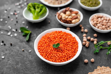 Superfoods on a gray background with copy space. Nuts, beans, greens and seeds. Healthy vegan food