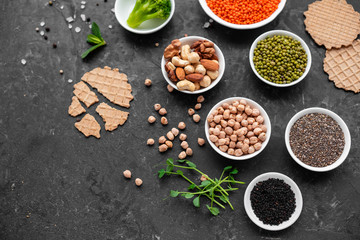 Superfoods on a gray background with copy space. Nuts, beans, greens and seeds. Healthy vegan food