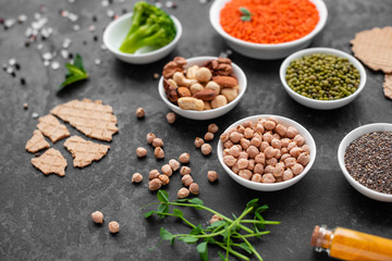 Superfoods on a gray background with copy space. Nuts, beans, greens and seeds. Healthy vegan food