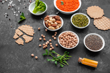 Superfoods on a gray background with copy space. Nuts, beans, greens and seeds. Healthy vegan food