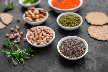 Superfoods on a gray background with copy space. Nuts, beans, greens and seeds. Healthy vegan food