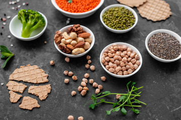 Superfoods on a gray background with copy space. Nuts, beans, greens and seeds. Healthy vegan food