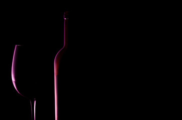 Silhouette of glass of red wine and bottle. Black background.
