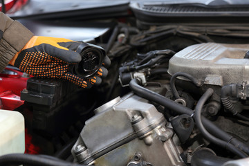 Fototapeta Dłoń w rękawiczce trzyma korek wlewu oleju do silnika samochodu. obraz