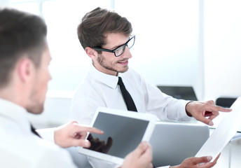 Obraz premium Team of two businessmen discussing new project using tablet and dokuments in the office.