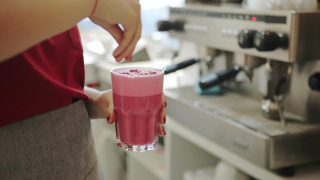 Crop female bartender spilling sweet decorations on yummy pink beverage in cafe