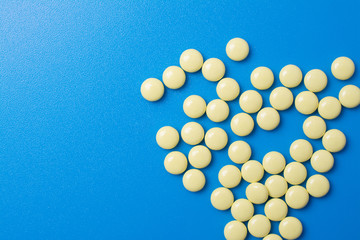 yellow pills on blue background, top view