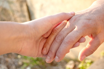 Adult and young women holding hands.