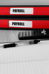 Red folders with payroll written on the label on a desk with selective colour