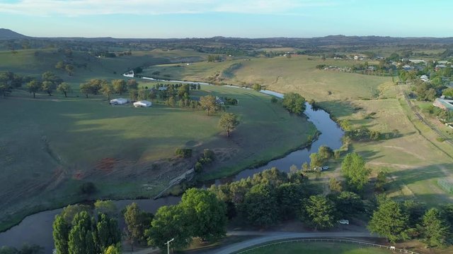 Slow aerial descend over rural area and river at sunset in Australia