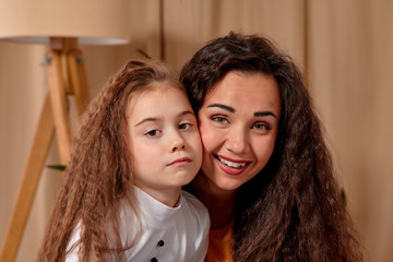 Love of young mother and daughter. They sit on the bed at home and have fun