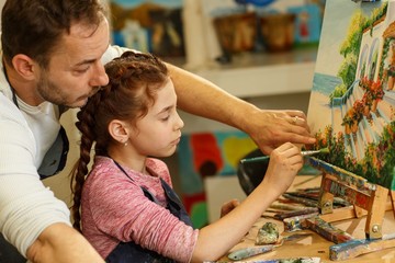 View of artist father and little daughter against oil picture thinking about creativity ideas and...