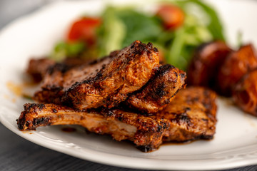 Lamb chops on a plate with vegetables and some potatoes.​
