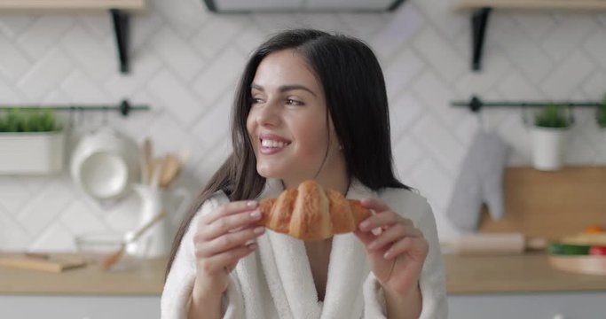 Happy girl smelling croissant in the breakfast 