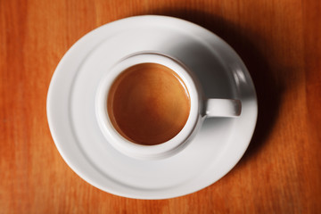 White coffee Cup with delicious foam, close-up top view on wooden background. Concept of coffee break and serving coffee