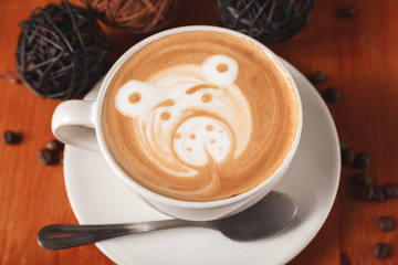 Cappuccino coffee with latte art in the form of bear close-up on a wooden table. The concept of coffee in the cafe
