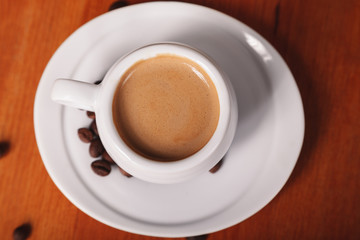 White coffee Cup with thick milk foam, close-up top view on wooden table. Concept of coffee break and serving coffee