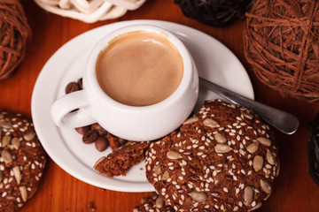 White coffee Cup with thick milk foam and cookies, closeup on a wooden table. Concept of coffee break and serving coffee