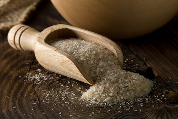 Heap of psyllium husk also called isabgol in wooden scoop and bowl on table