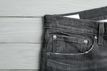 Jeans pocket on wooden background, space for text