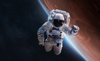 Astronaut float in outer space over of the planet Mars on the background. Elements of this image...