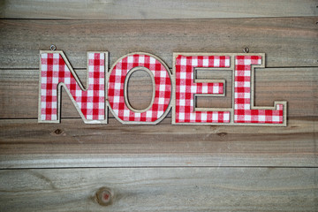Rustic Christmas background with the word NOEL in red and white plaid. Wood background, copyspace room