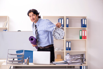 Young handsome male employee doing exercises in the office 